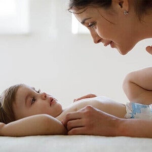 Photo of mother smiling and leaning over baby on changing mat