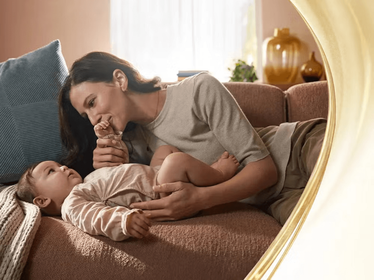 Photo of mother and toddler cuddling on couch in warm living room